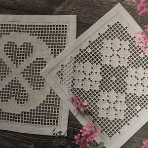 May include: Two white linen tablecloths with intricate embroidered designs. One tablecloth features a pattern of three hearts, while the other features a pattern of flowers.