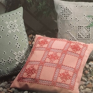 Peut inclure: Trois coussins décoratifs avec des motifs de flocons de neige brodés. Les coussins sont dans des tons de vert, blanc et rose.