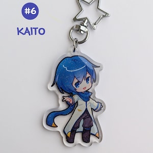 May include: A clear acrylic keychain featuring a blue-haired anime character with a white coat and blue scarf. The keychain has a silver star-shaped clasp and a ring. The text "#6 KAITO" is in a blue circle.
