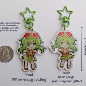 May include: Two anime-style acrylic keychains, each featuring a green-haired character with red-tinted sunglasses. The keychains are 2.5 inches tall and have a glitter epoxy coating on the front. Each keychain has a green star-shaped clasp.