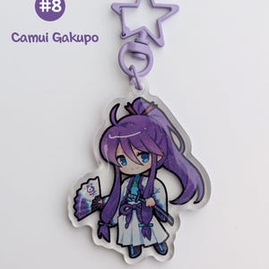 May include: A clear acrylic keychain featuring a cartoon character with long purple hair, blue eyes, and a white outfit. The keychain has a star-shaped clasp and the text "#8 Camui Gakupo".