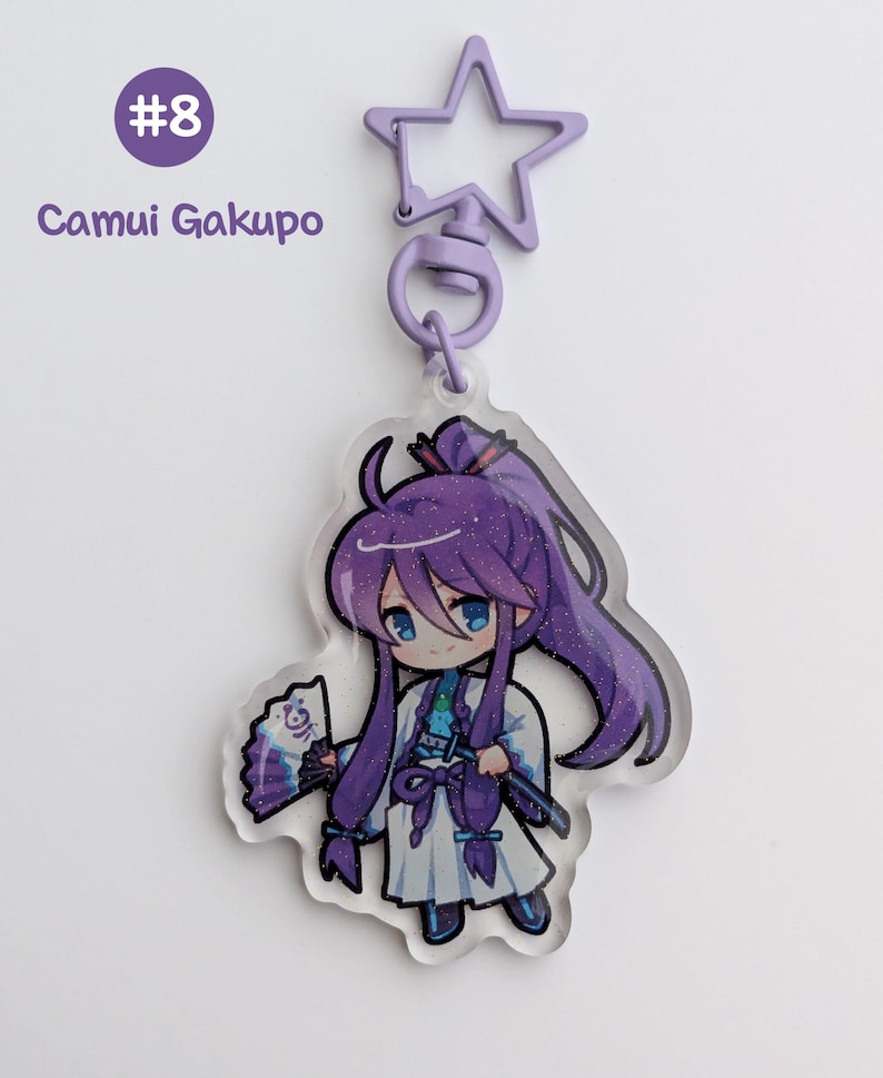 May include: A clear acrylic keychain featuring a cartoon character with long purple hair, blue eyes, and a white outfit. The keychain has a star-shaped clasp and the text "#8 Camui Gakupo".