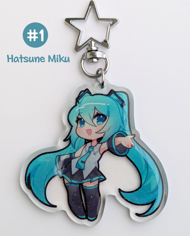 May include: A clear acrylic charm featuring a cartoon character with long, turquoise hair and a matching outfit. The charm is attached to a silver-colored star-shaped keychain. The text "#1 Hatsune Miku" is printed on the top left.