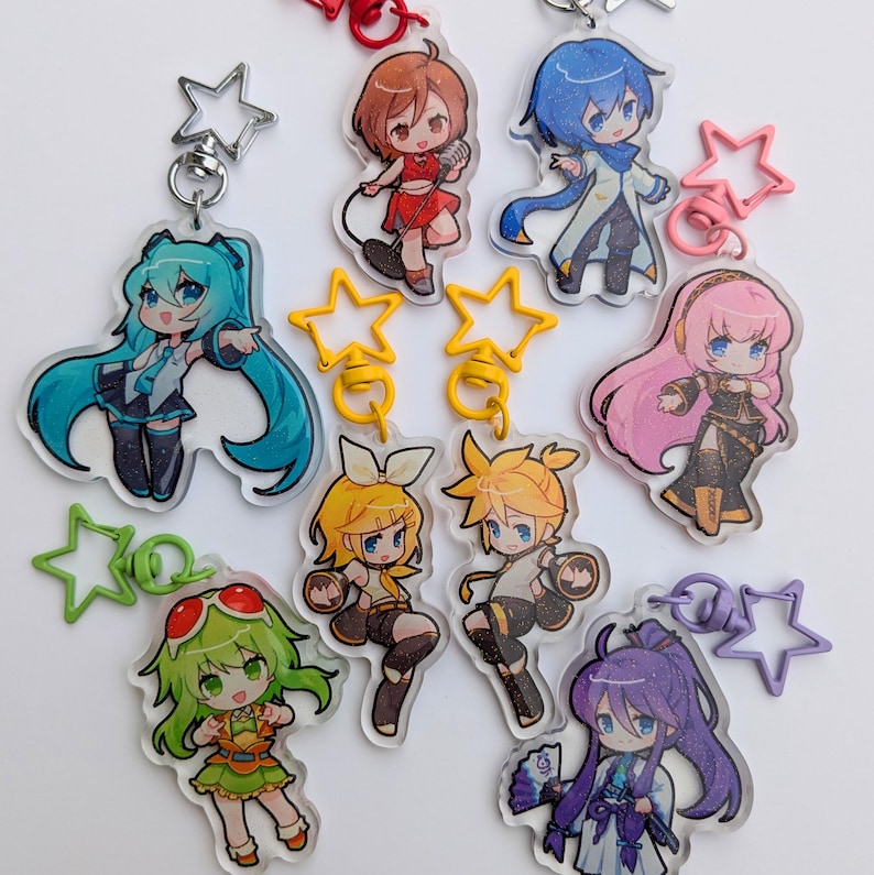 May include: Collection of anime-style character keychains. Each keychain features a different character with vibrant hair colors and outfits. The keychains are made of clear acrylic and have star-shaped clasps. The characters are in various poses.