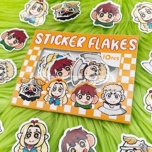 May include: A package of "STICKER FLAKES" with 10 pieces, featuring cartoon character stickers. The stickers have various designs, including characters with blonde and brown hair, and some with helmets. The package is orange and white checkered.