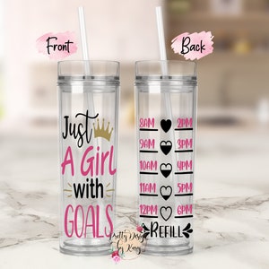 May include: A clear plastic tumbler with a black and pink design. The front of the tumbler says "Just A Girl with GOALS" with a gold crown. The back of the tumbler has a black and pink design with a water tracker and the words "REFILL".
