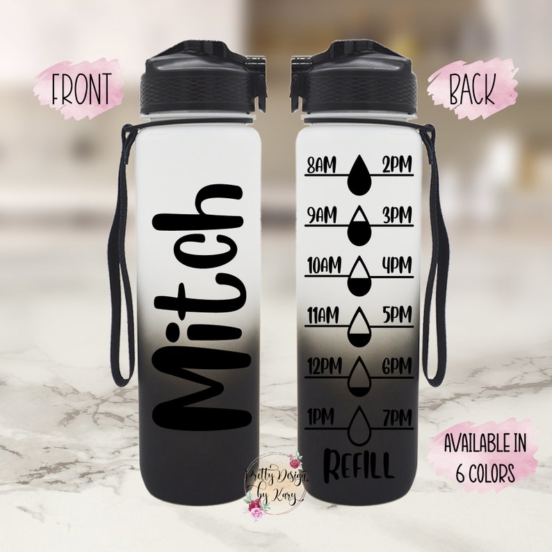 Puede incluir: Una botella de agua negra y blanca con una correa negra. La botella tiene un dise&ntilde;o degradado en blanco y negro. La parte delantera de la botella tiene el nombre "Mitch" escrito en negro. La parte posterior de la botella tiene un recordatorio de agua basado en el tiempo con el texto "REFILL" en la parte inferior.