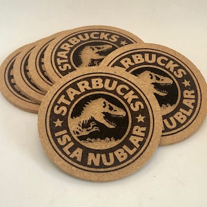 May include: A stack of eight brown cork coasters with a black and white logo that says "Starbucks Isla Nublar" and a dinosaur silhouette.