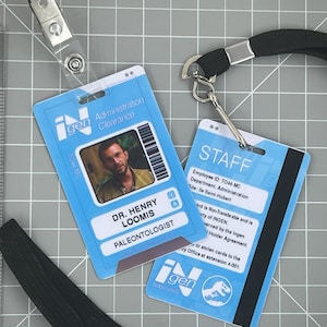 May include: Two blue iGen ID badges with lanyards. One badge features a photo of a man and the text "DR. HENRY LOOMIS, PALEONTOLOGIST." The other badge reads "STAFF" and includes employee information.