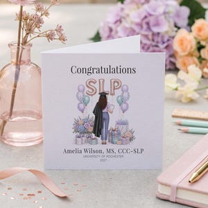 May include: A square greeting card featuring a graduation illustration of a person in a cap and gown with the text Congratulations SLP, Amelia Wilson, MS, CCC-SLP, University of Rochester, 2027. The design includes balloons, gifts, and flowers.