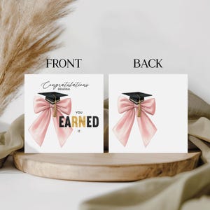 May include: A graduation card with a black mortarboard and a pink bow. The front of the card reads "Congratulations Brianna, You Earned It" in black and gold lettering. The back of the card features the mortarboard and bow.