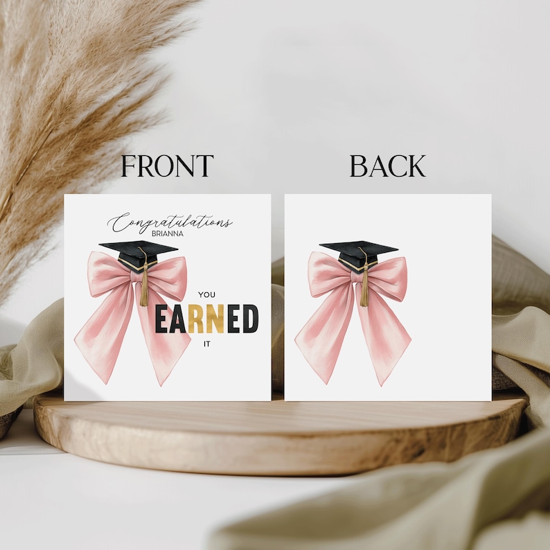 May include: A graduation card with a black mortarboard and a pink bow. The front of the card reads "Congratulations Brianna, You Earned It" in black and gold lettering. The back of the card features the mortarboard and bow.