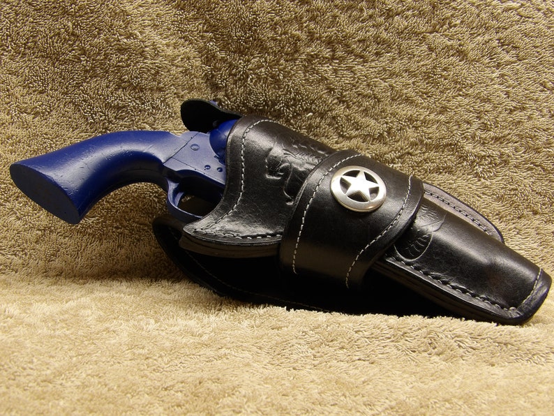 May include: A blue revolver pistol in a black leather holster with a silver star on the strap.