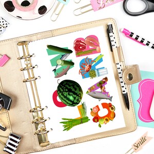 May include: A gold binder with a white page open to a page with the word "MEAL" spelled out in colorful food images. The page is surrounded by various office supplies, including a stapler, a pair of scissors, a pen, and a pink and black polka dot sticker.