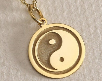 May include: A gold necklace with a round pendant featuring a yin yang symbol.