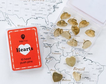 Könnte beinhalten: Ein Set mit 10 goldenen herzförmigen Stecknadeln in einem durchsichtigen Plastikbehälter. Der Behälter befindet sich auf einer Weltkarte mit dem Text "Hearts 10 heart push pins" auf einem roten und weißen Etikett.