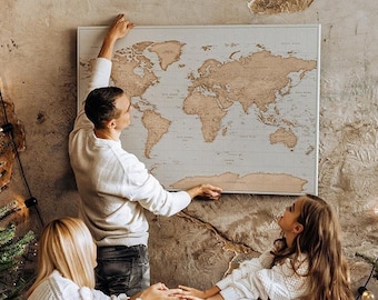 May include: A rectangular world map wall art piece featuring light-colored wooden continents mounted on a neutral background, displayed in a frame and positioned on a textured wall above a brown sofa.