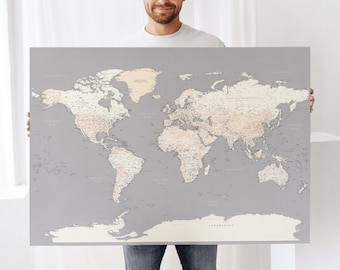 May include: A person holding a large world map with a gray background and beige continents. The map is detailed with country borders and city names.