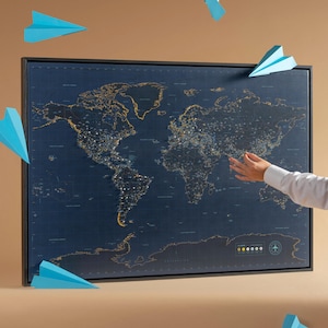 May include: A framed world map with a dark blue background and gold-coloured city lights. The map is surrounded by blue paper aeroplanes. A person's hand points towards the map.