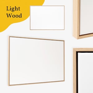 May include: Several rectangular, light wood framed canvases are displayed against a white wall. The canvases have a clean, minimalist aesthetic, with a bright white surface. The words "Light Wood" are in black text in the upper left corner.
