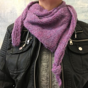 Op de afbeelding: Een paarse gebreide sjaal met een subtiel ombre-effect, gedragen om de nek van een persoon die een zwart leren jack draagt.