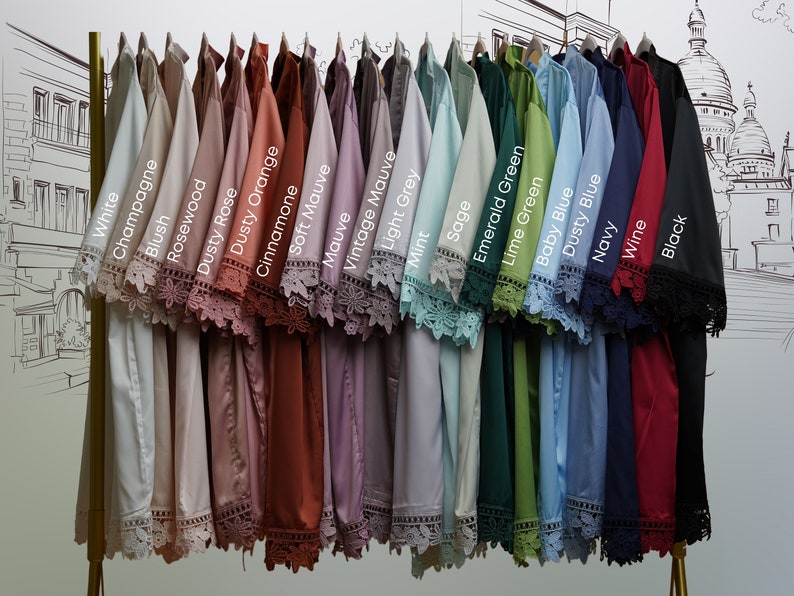 May include: A display of 20 different colored shirts with lace trim on the sleeves. The colors are white, champagne, blush, rosewood, dusty rose, dusty orange, cinnamone, soft mauve, mauve, vintage mauve, light grey, mint, sage, emerald green, lime green, baby blue, dusty blue, navy, wine, and black.