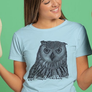 Könnte beinhalten: Ein hellblaues T-Shirt mit einer schwarzen und weißen Grafik eines Eulen mit dem Text "owl scale shibou" darunter.