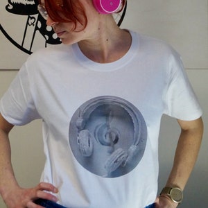May include: A white t-shirt featuring a black and white graphic of a person wearing headphones. The graphic is a circular design with concentric circles.