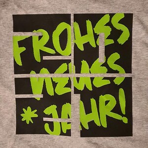 Puede incluir: Una camiseta gris con un gr&aacute;fico negro y verde que dice "Frohes Neues Jahr!"