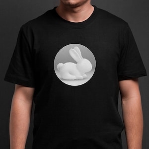 Könnte beinhalten: Schwarzes T-Shirt mit einer weißen Grafik eines Hasen in einem Kreis. Das Hasen-Design wird mit konzentrischen Linien erstellt, was einen 3D-Effekt erzeugt. Das T-Shirt hat einen klassischen Rundhalsausschnitt.