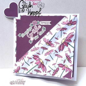 May include: A purple card with a heart-shaped flap on the front. The card has a white background with pink flowers and a purple and white striped pattern. The text on the card reads "Blumige Grüße für dich" and "Peppercus Design".