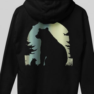 May include: Black hoodie featuring a silhouette of a bear and a cub in a woodland scene. The bear and cub are positioned in front of a moon with a blue, green and yellow gradient.