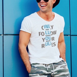 Könnte beinhalten: Ein weißes T-Shirt mit einer blauen und grauen Grafik, auf der "ONLY TRUST FOLLOW YOUR RULES" steht. Die Person, die das Shirt trägt, lächelt und trägt einen schwarzen Hut und eine Sonnenbrille.