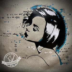 Op de afbeelding: Een canvas kunstwerk met een profiel van een vrouw met zwart haar en lippen. Het kunstwerk heeft een neutraal kleurenpalet met teal accenten en handgeschreven tekst. Het logo van de kunstenaar is zichtbaar in de linker benedenhoek.