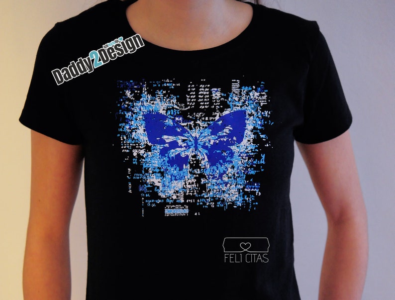 Op de afbeelding: Zwart T-shirt met een blauwe vlinderprint op een witte en zwarte gepixelde achtergrond. De tekst "Feli Citas" is onderaan het shirt gedrukt.