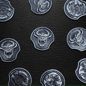 Puede incluir: Una colección de nueve fichas de metal plateadas con varios diseños. Cada ficha presenta una criatura o símbolo diferente, incluyendo una cabeza de demonio, una araña y una espiral.