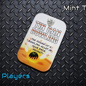 Puede incluir: Una lata rectangular de menta con las palabras "TIN CAN BOWLING" en letras grandes. La lata presenta un diseño de bolera con bolos y una bola de bolos en llamas. El texto en la lata dice "THE POWER OF A BOWLING ALLEY IN YOUR BACK POCKET!!" y "1+ Players."