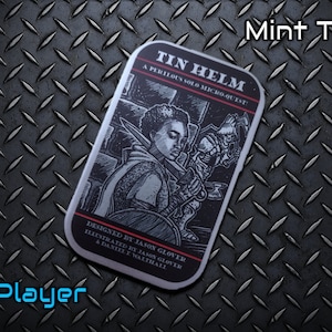 May include: A rectangular mint tin with a black and white illustration of a person in armor, with the text "TIN HELM" and "A PERILOUS SOLO MICRO-QUEST." The tin is labeled "1 Player" and "Mint Tin!"