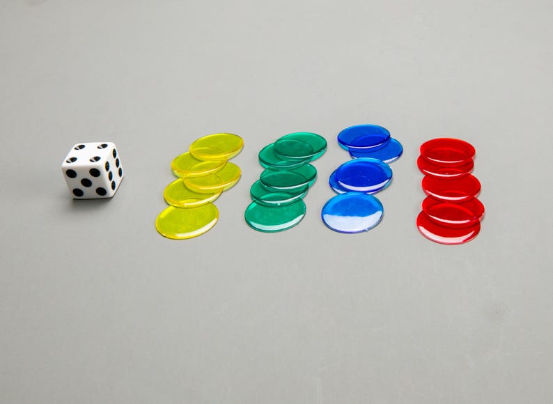 Puede incluir: Un dado blanco con puntos negros y cinco pilas de fichas de juego de colores. Las fichas son amarillas, verdes, azules y rojas.
