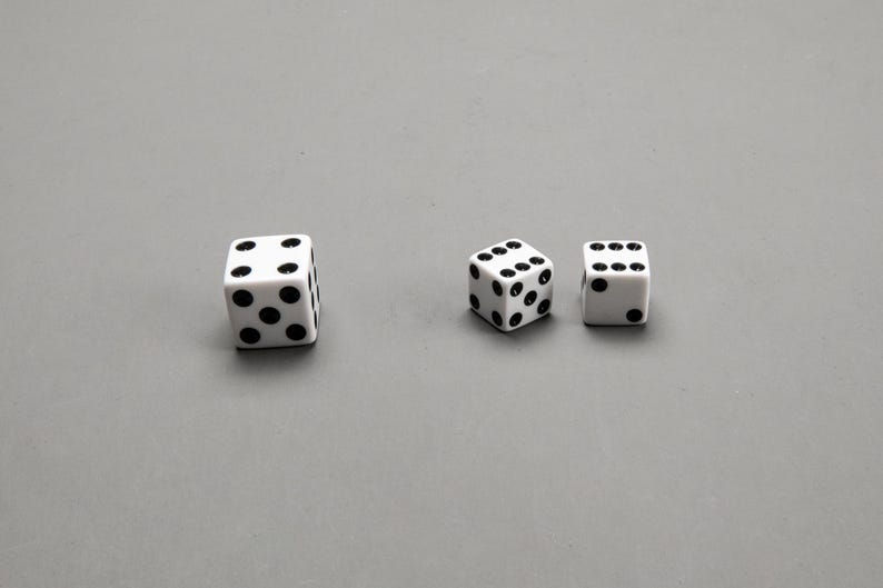 Puede incluir: Tres dados blancos con puntos negros, dos son m&aacute;s peque&ntilde;os y uno es m&aacute;s grande.