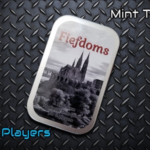 May include: A silver tin with a black and white image of a medieval castle and the text "Fiefdoms" in red. The text "A Real-time Medieval Dice Game for 2 players" is printed below the image. The tin is labeled "Mint Tin!" and "2 Players" in blue.