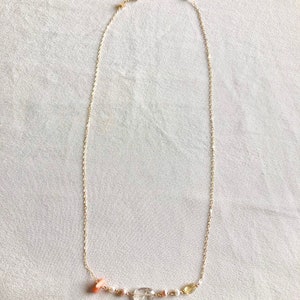May include: A delicate gold chain necklace with a small cluster of pink, white, and yellow gemstones.