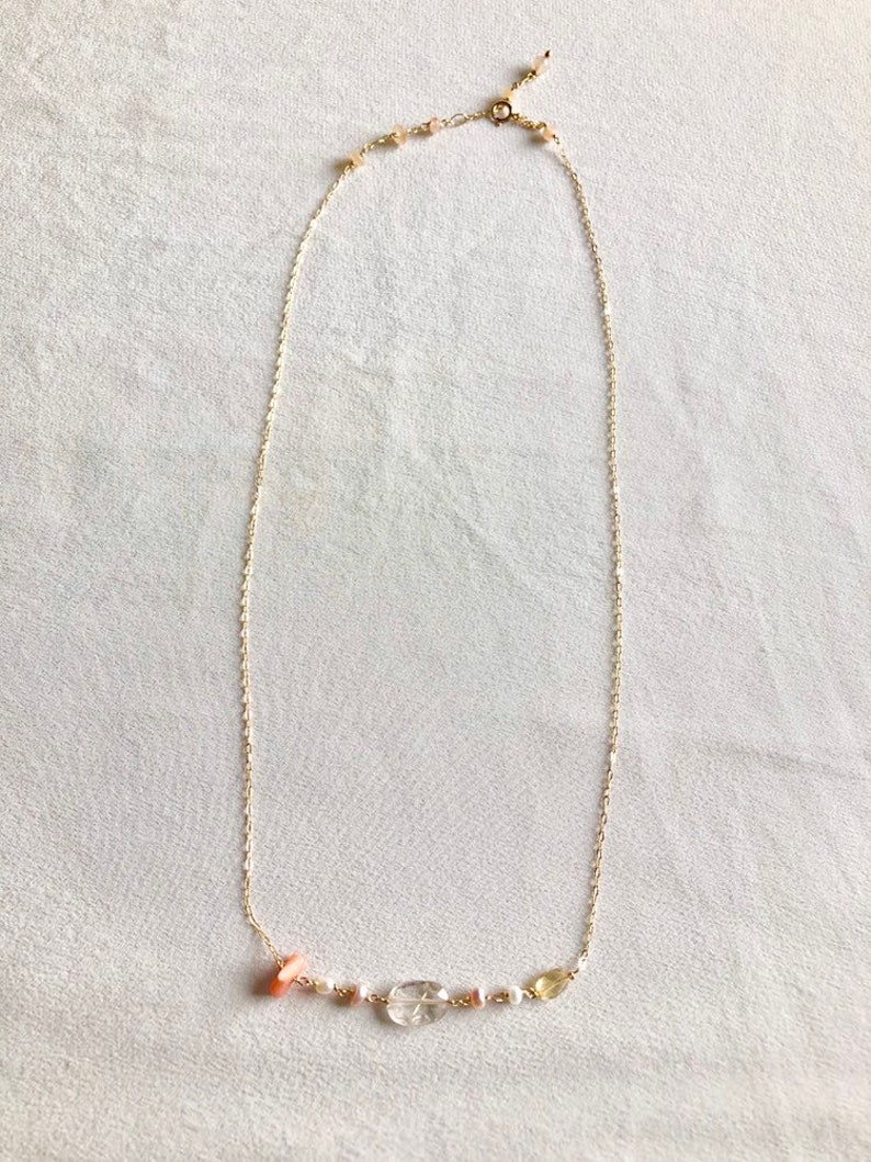 May include: A delicate gold chain necklace with a small cluster of pink, white, and yellow gemstones.