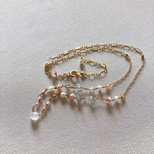 Puede incluir: Un delicado collar de cadena de oro con un dise&ntilde;o en capas. El collar presenta una variedad de peque&ntilde;as piedras preciosas en tonos de rosa, azul y blanco, as&iacute; como peque&ntilde;os acentos de perlas.