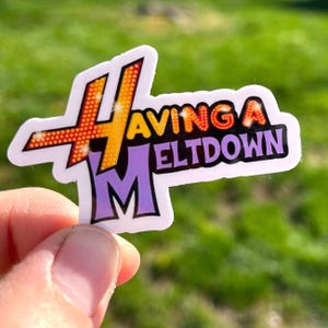 May include: A white sticker with a yellow and orange "4" with a purple "M" and the text "Having a Meltdown" in orange and red.