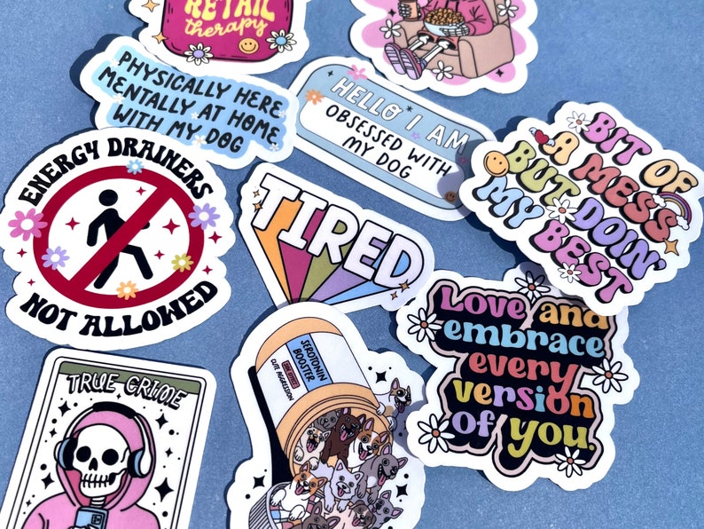 May include: A collection of colorful stickers with various phrases and designs. Some of the stickers include "Energy Drainers Not Allowed", "Bit of a Mess But Doin My Best", "Love and Embrace Every Version of You", "True Crime", "Tired", "Hello I Am Obsessed With My Dog", and "Physically Here Mentally At Home With My Dog".