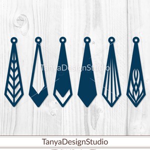 May include: Six navy blue earring designs with various geometric and abstract cut-out patterns. Each earring has a small circular hole at the top for hanging. The earrings are displayed on a light wood grain background.