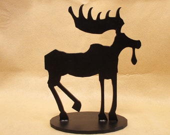 May include: Black metal moose silhouette sculpture on a black base. The moose has a large, stylized antler and a long, thin snout.