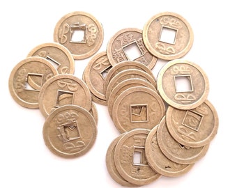 May include: A pile of 13 Chinese lucky coins with a square hole in the center. The coins are made of brass and have Chinese characters on them.
