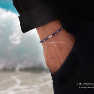 Puede incluir: Una pulsera de cuentas con cuentas azul marino y plateadas alternas. La pulsera se lleva en la mu&ntilde;eca, con un fondo oscuro. Un accesorio sencillo y elegante.
